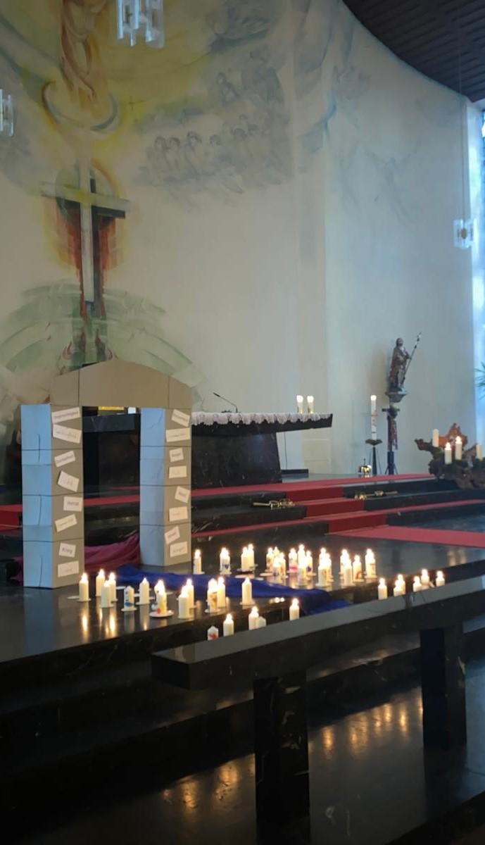 Im Altarraum der Hütterdorfer Kirche ist ein Tor zu sehen, davor stehen Kerzen
