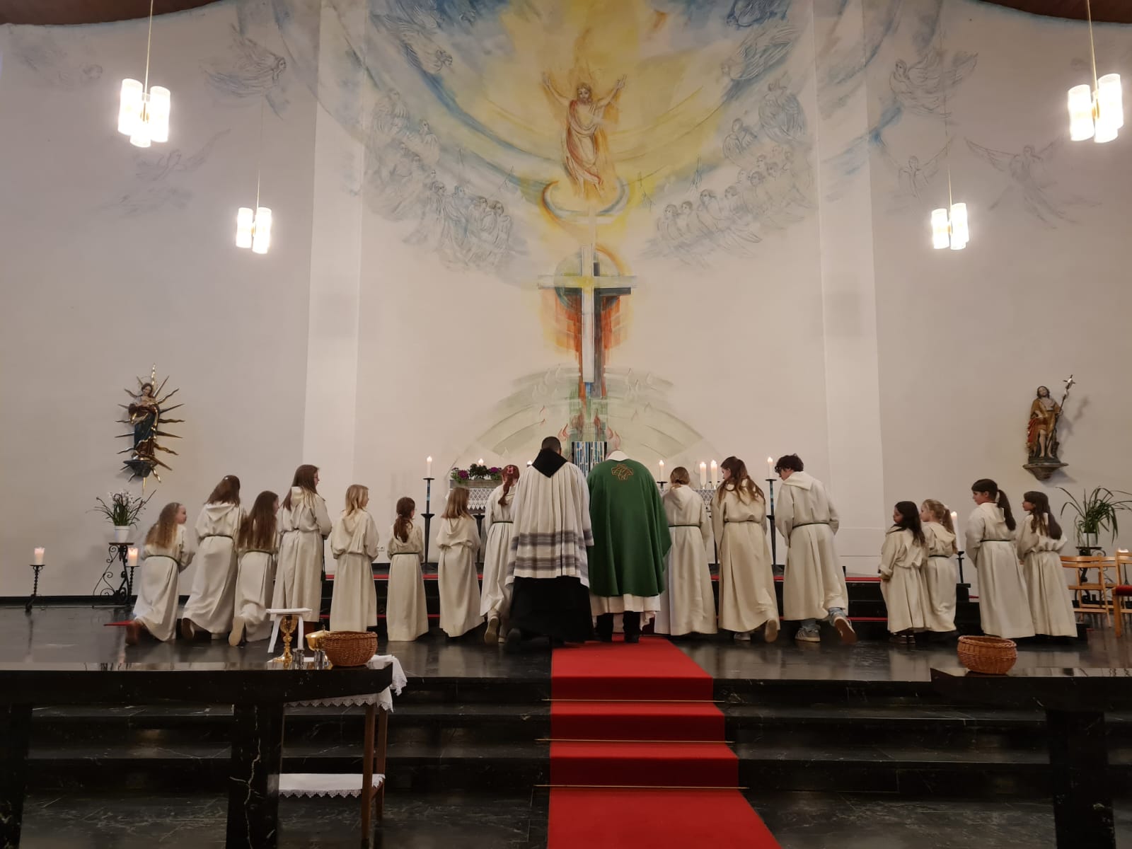 PFarrer und Messdiener*innen stehen vor dem Altar