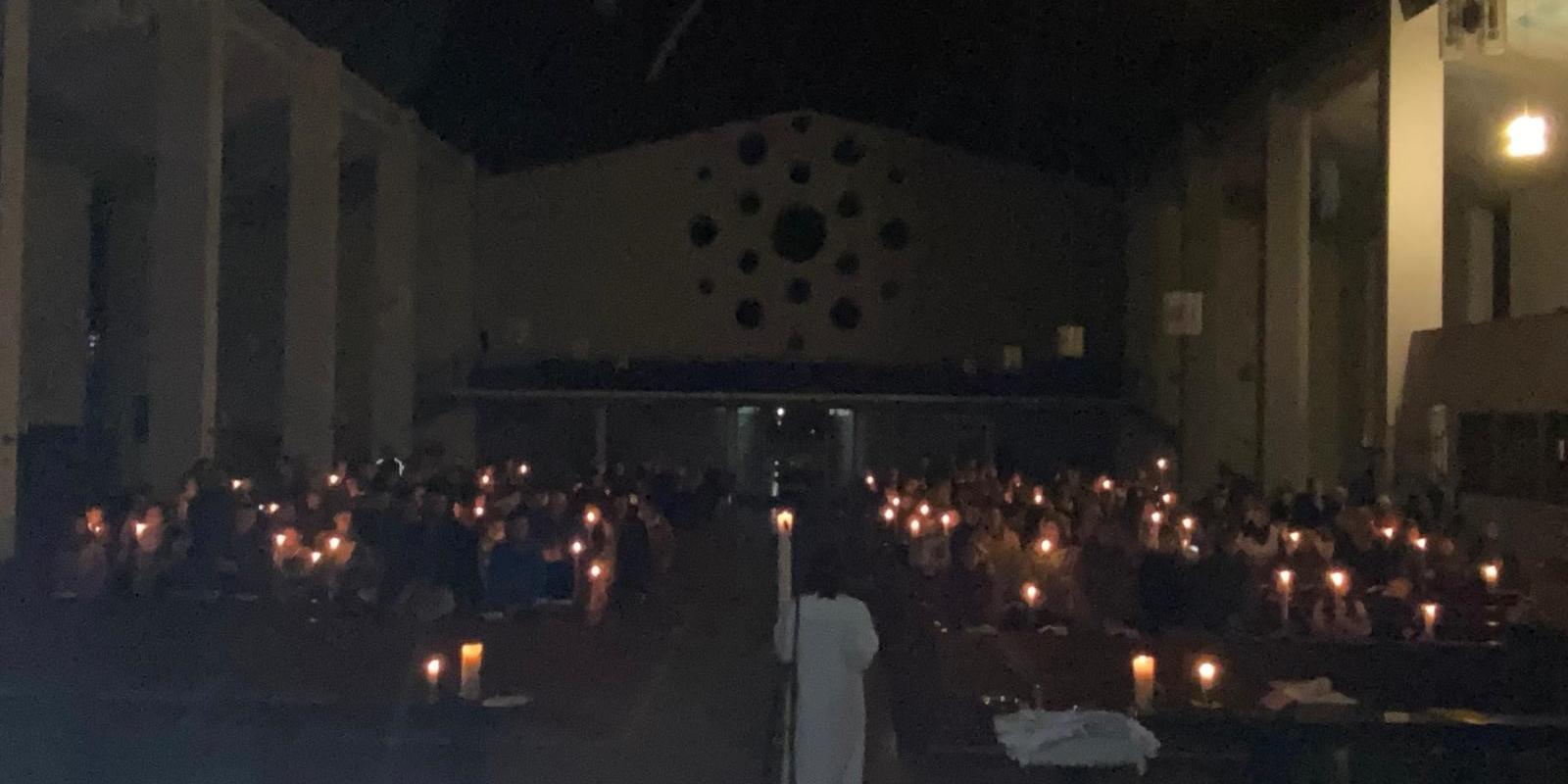 Eine dunkle Kirche wird von Kerzen erhellt.